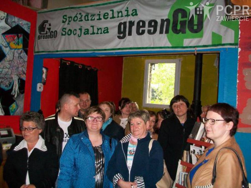 Zdjęcie: Uczestniczki i uczestnicy wyjazdu stoją na tle baneru spółdzielni GreenGo